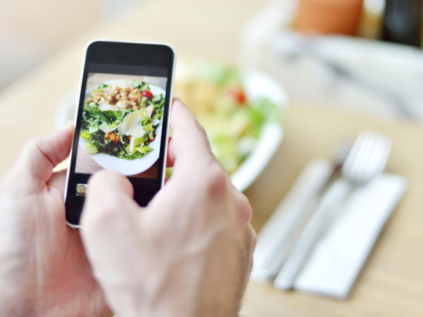 Young man making picture from her food with smartphone.