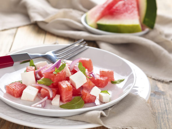Watermelon salad with feta, mint and red onion. On wooden rustic table.