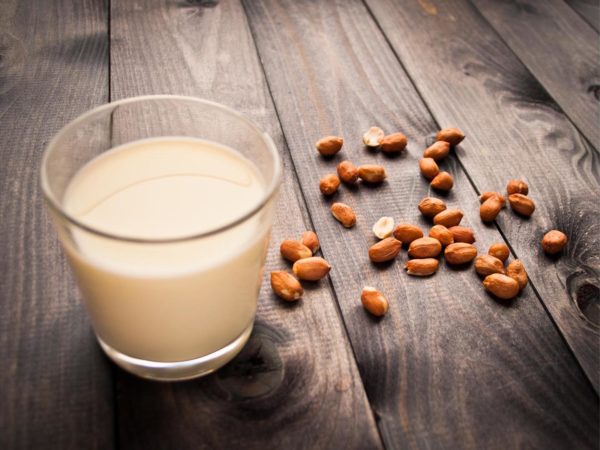 Glass of milk and some peanuts on wooden surface