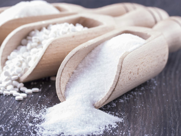 Food ingredients - sugar, aspartame and salt on a dark solid wooden background.