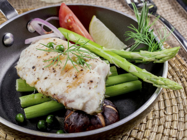 Grilled salmon and vegetables on dining table.