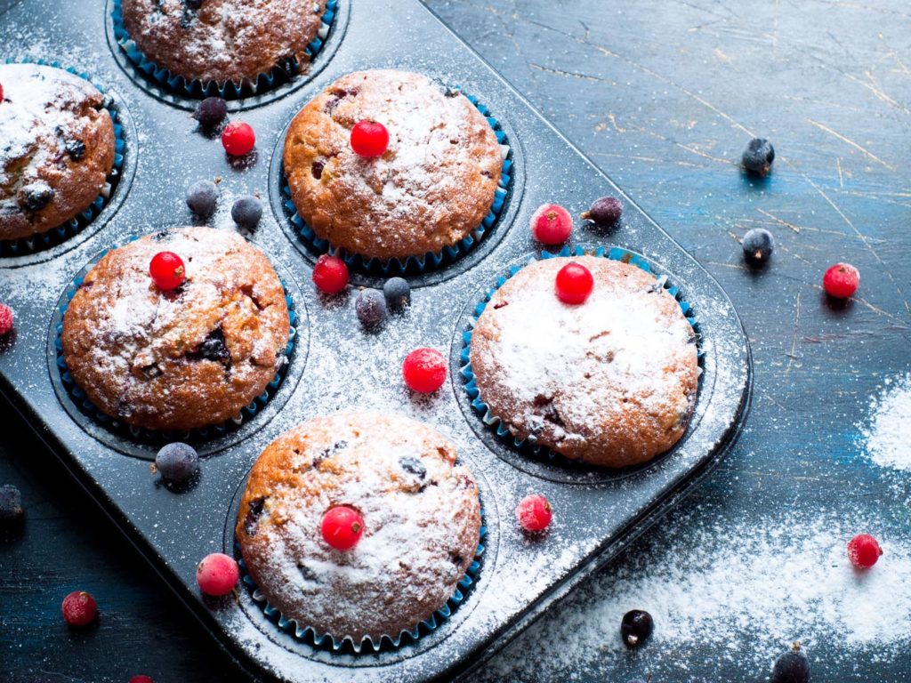 Muffins with red and black currant sprinkled with powdered sugar.