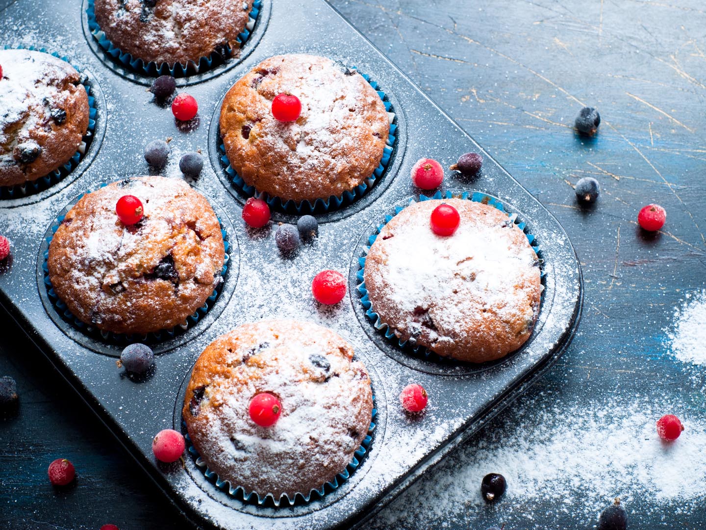 Muffins with red and black currant sprinkled with powdered sugar.