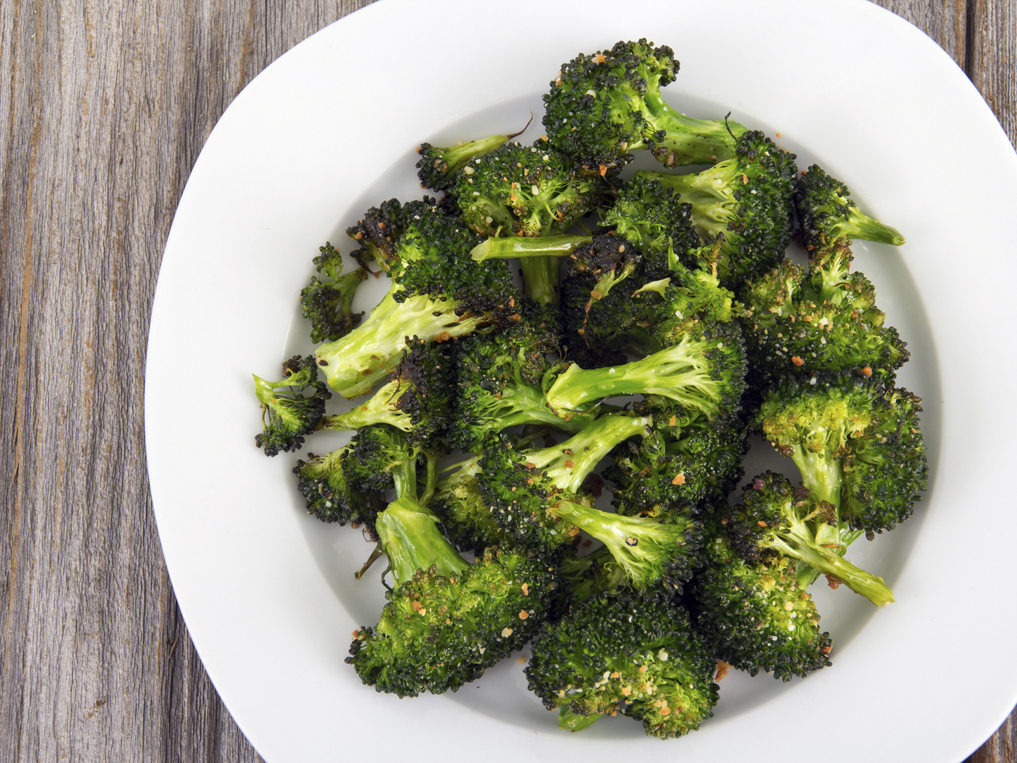 baked roasted garlic parmesan and olive oil broccoli side dish on wooden table