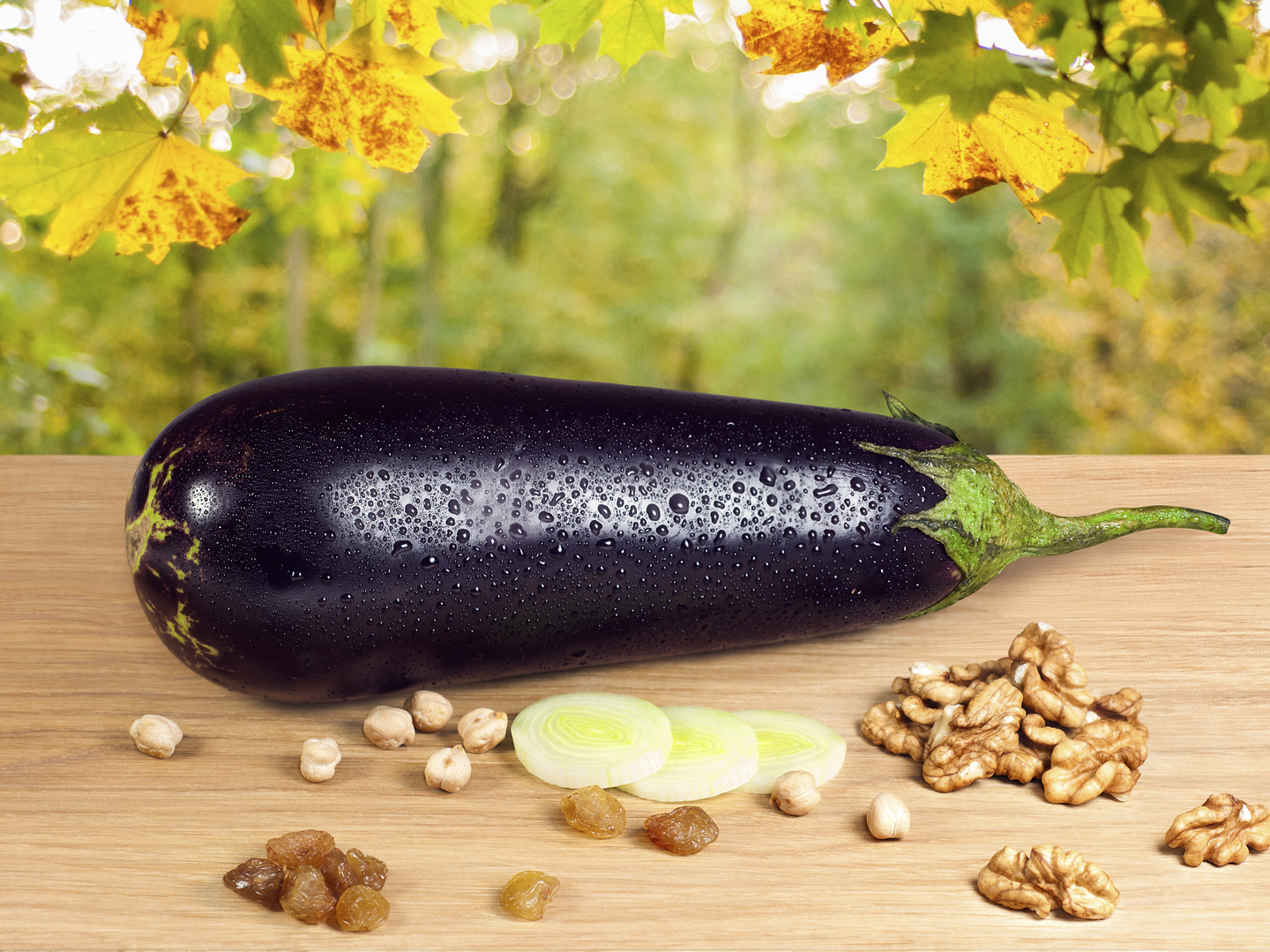 Fresh wet eggplant with sweet raisins and walnuts on a wooden table against a nature background