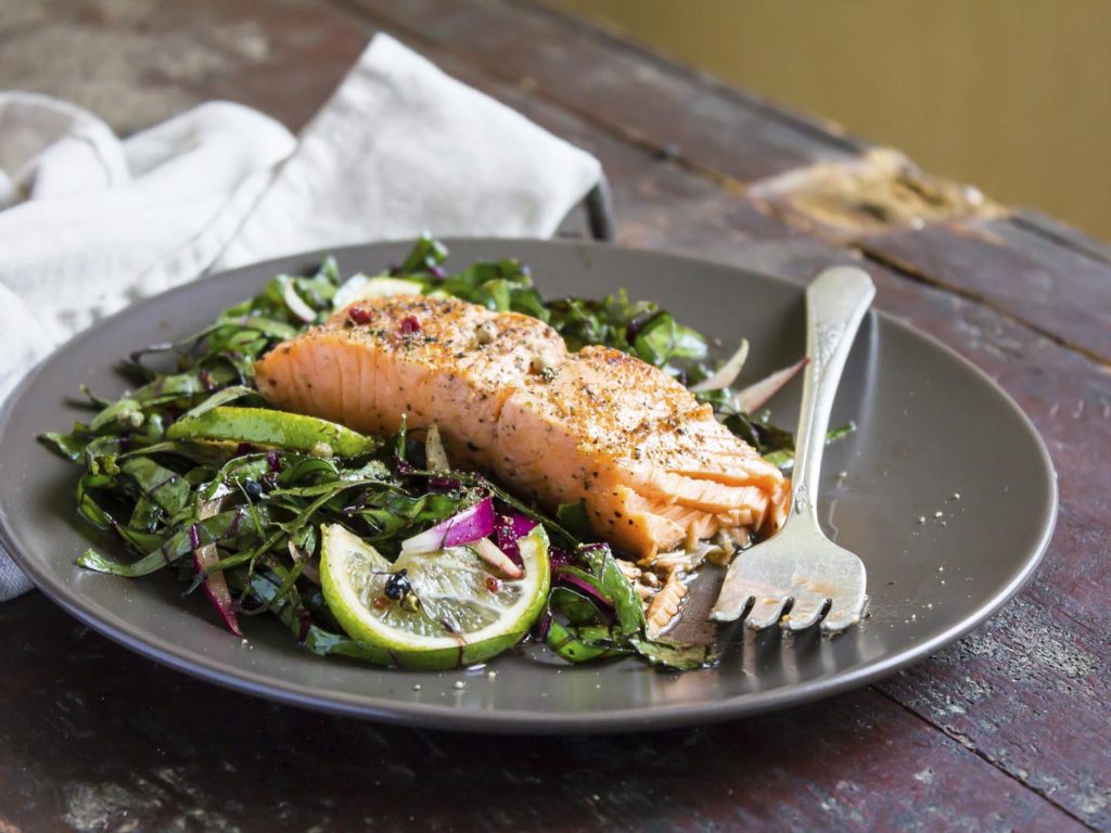 Roasted salmon fillet with fresh salad with onion and lime in a plate, selective focus