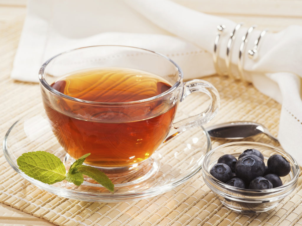 Cup of black tea with mint and fresh berries blueberry