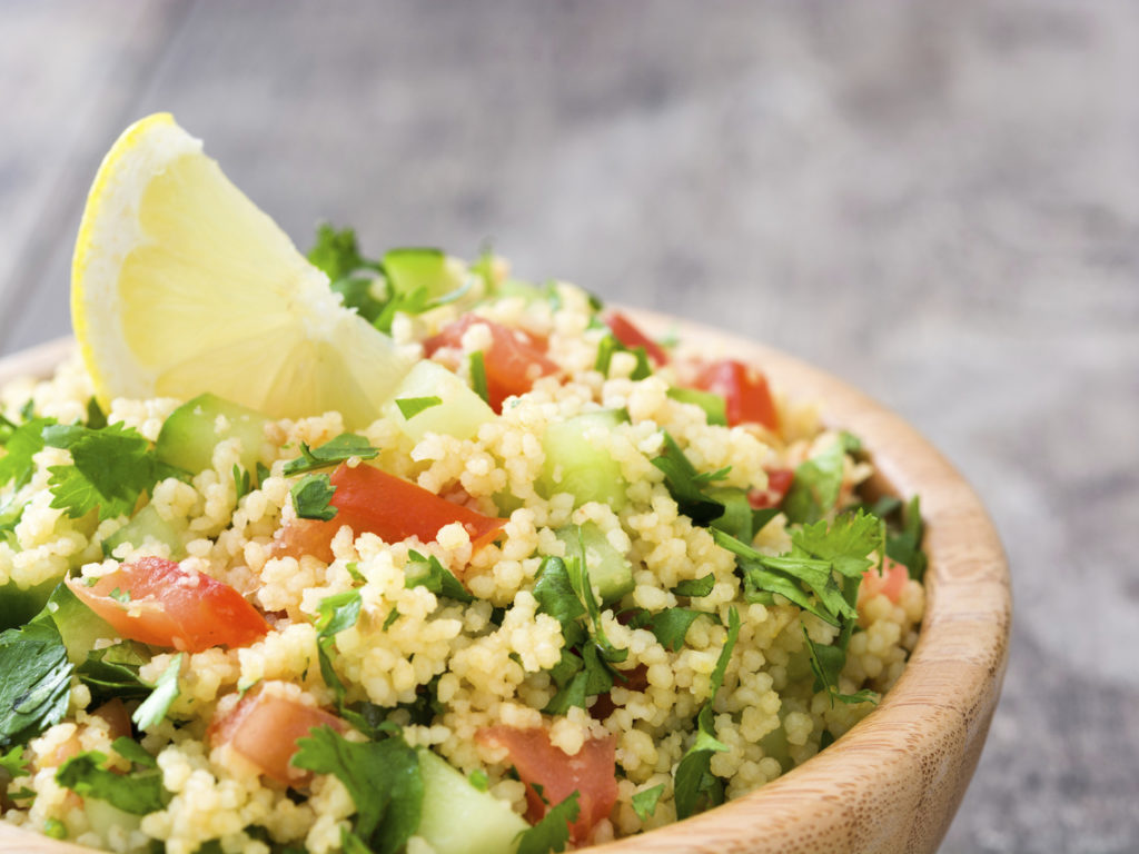 Tabbouleh salad with couscous on wooden background