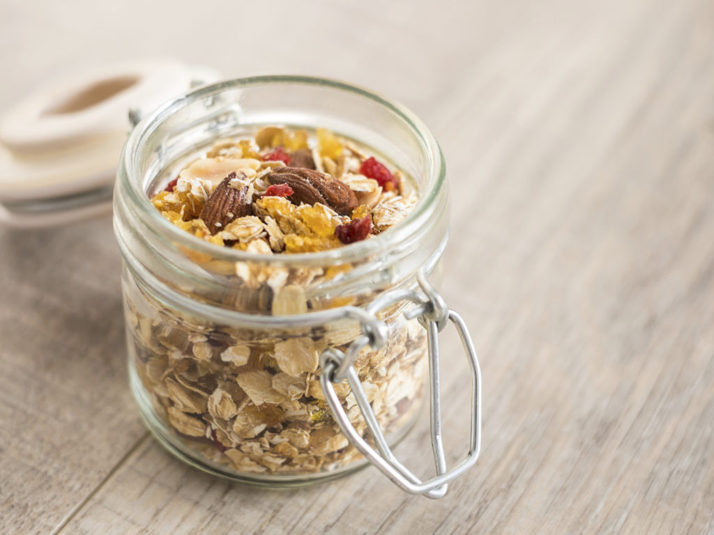 Homemade granola or muesli with oat flakes, dried cranberry, cherry, apricots, goji berries, toasted almonds and peanuts in a jar for breakfast or healthy snack, selective focus