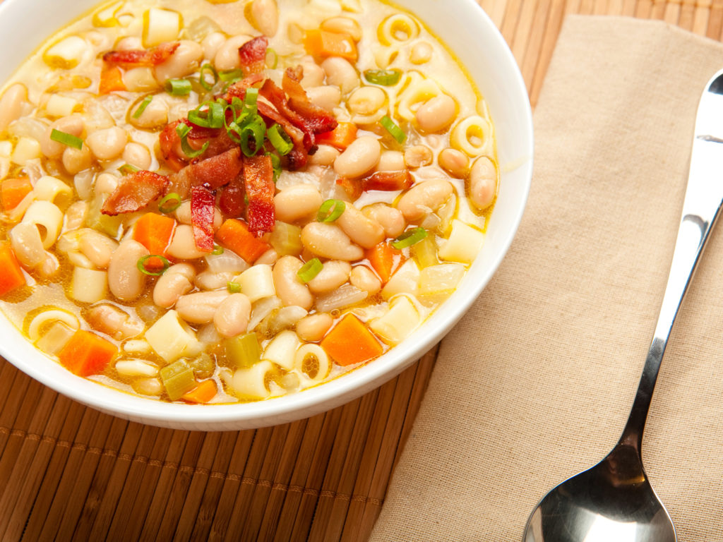 A hearty white bean soup topped with bacon and green onion