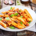 Italian penne pasta with tomato sauce, olives and basil