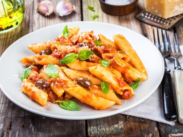 Italian penne pasta with tomato sauce, olives and basil