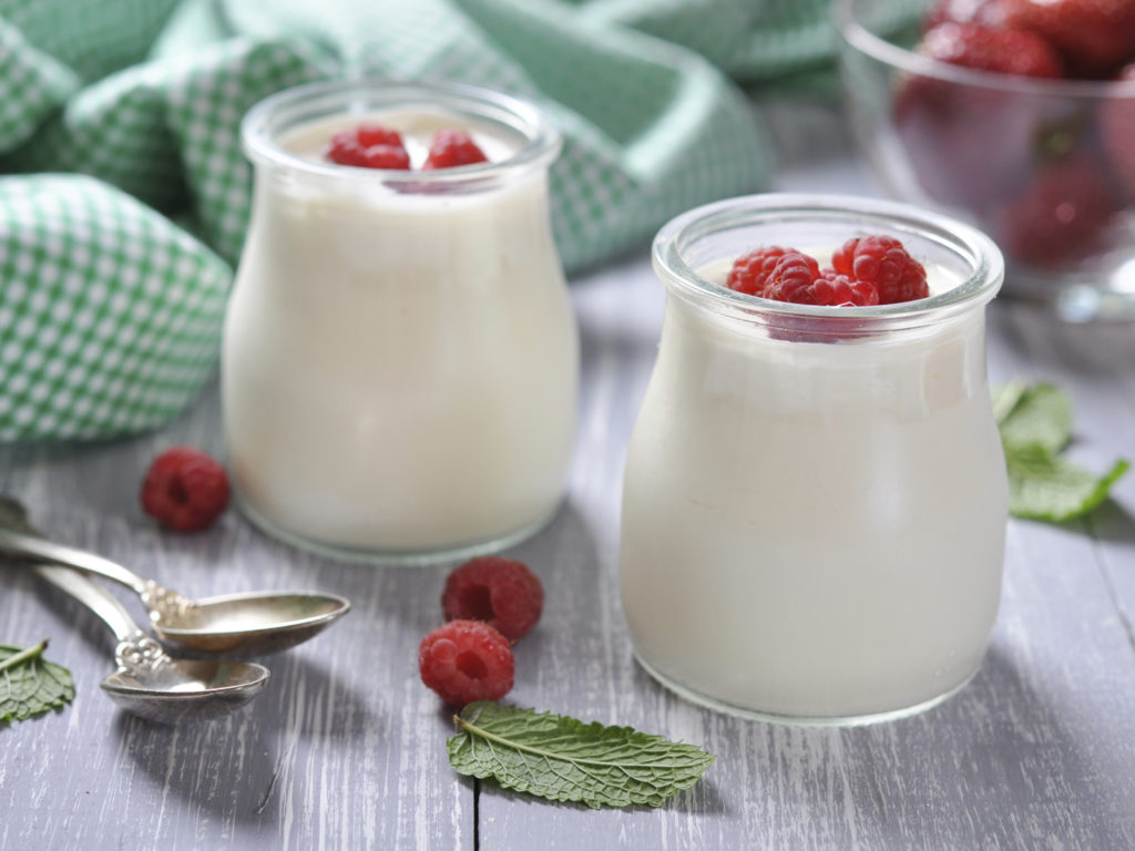 yogurt with ripe fresh raspberry in jars on wooden background