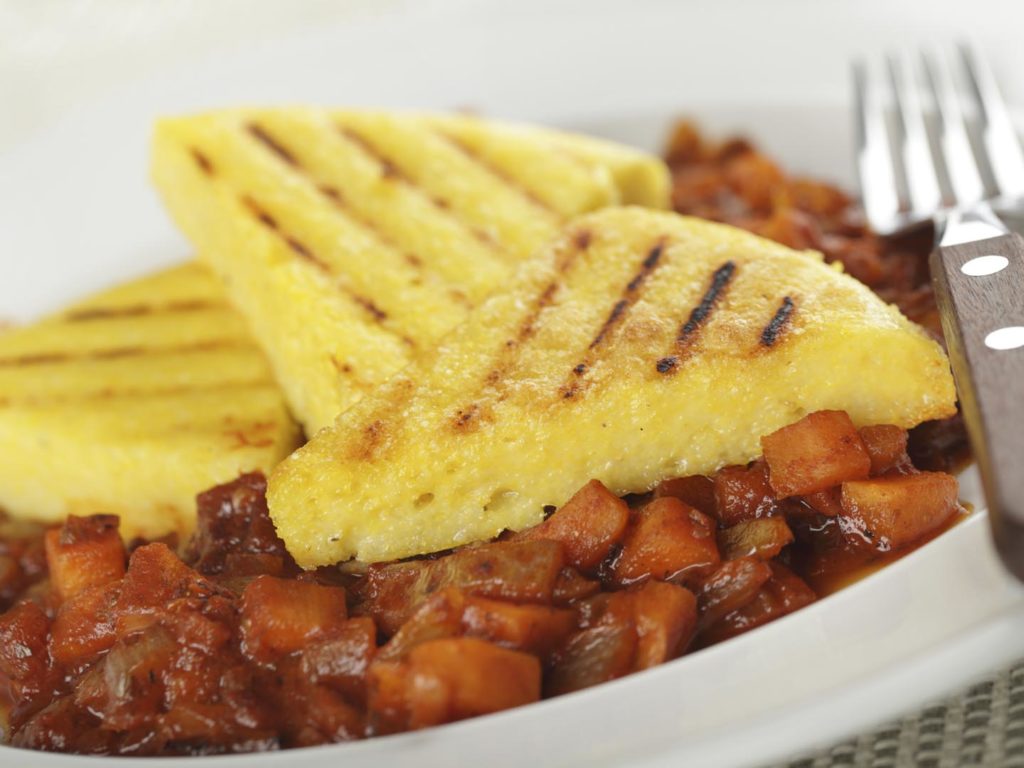 Polenta with carrot and onion on the white plate