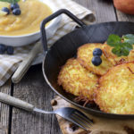 Homemade and crispy fried potato pancakes served in an iron pan with apple sauce