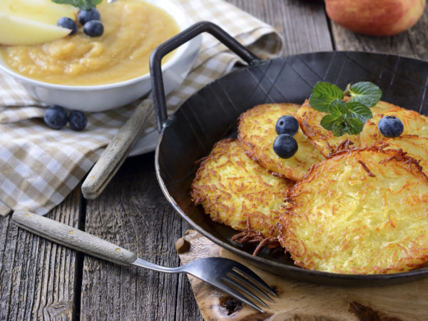 Homemade and crispy fried potato pancakes served in an iron pan with apple sauce