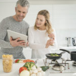 Couple cooking together at home following a recipe online on a tablet computer
