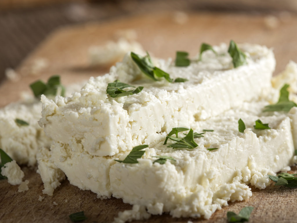 Fresh cheese slices on a wooden background with parsley