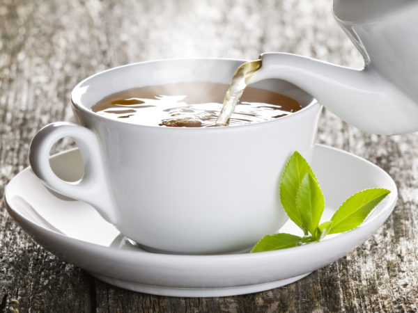 Cup of green tea pouring close up shoot