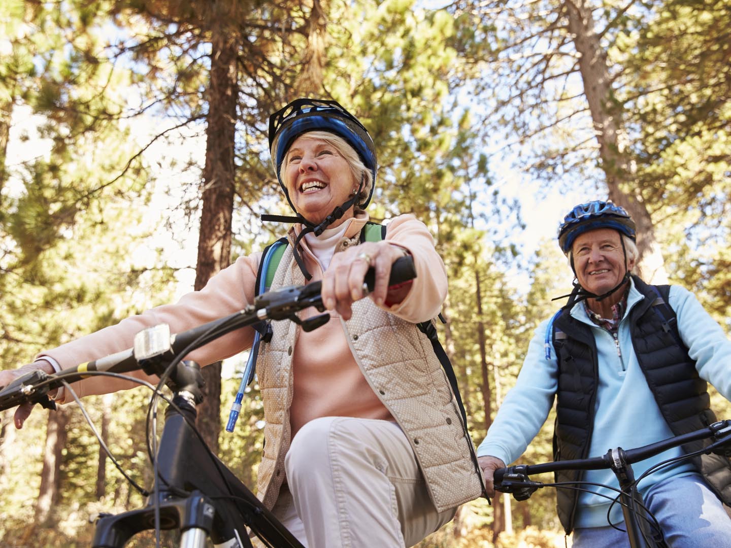 Senior couple mountain biking on a forest trail, low angle