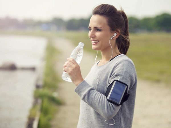 Female runner smiling while drinking bottled water