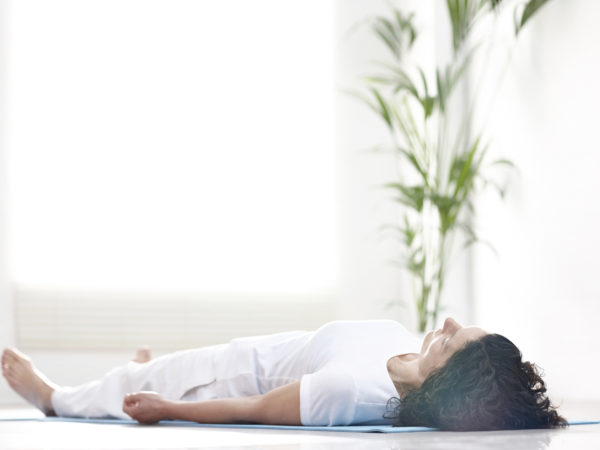 Mature woman lying on a yoga mat and relaxing after workout - Savasana