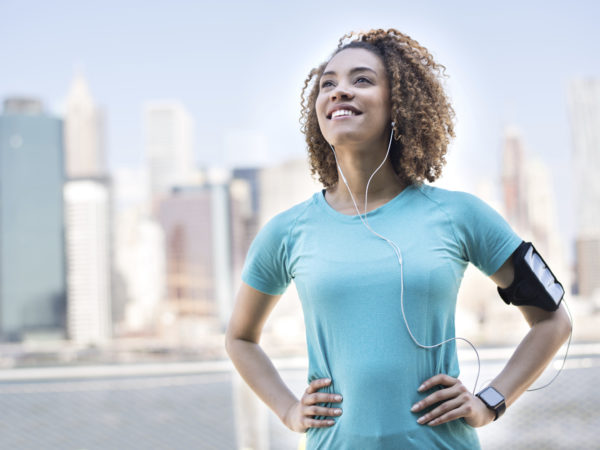 Thoughtful female runner outdoors listening to music on her cell phone and wearing an arm band