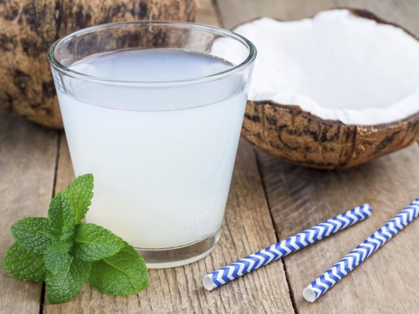 Coconut drink with pulp in glass on wooden table