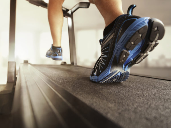 Man running in a gym on a treadmill concept for exercising, fitness and healthy lifestyle