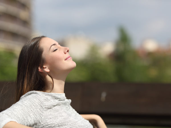 Urban woman sitting on a bench of a park and breathing deep fresh air