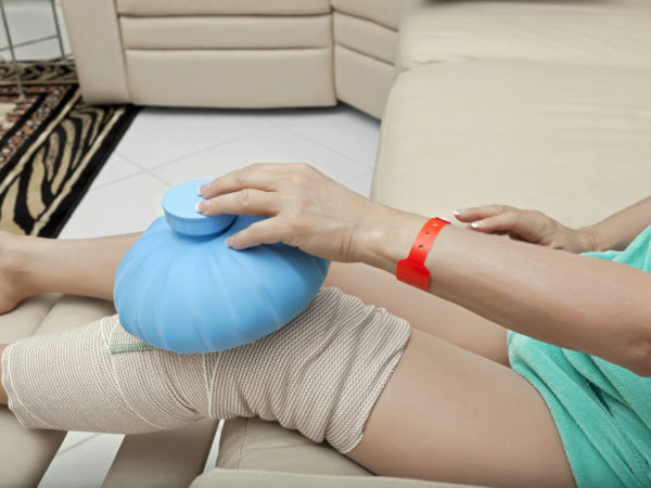 woman sitting with an ice bag on her knee after surgery. She is wearing a red allergy alert braceletClick here to view my other Medical images  a.m.