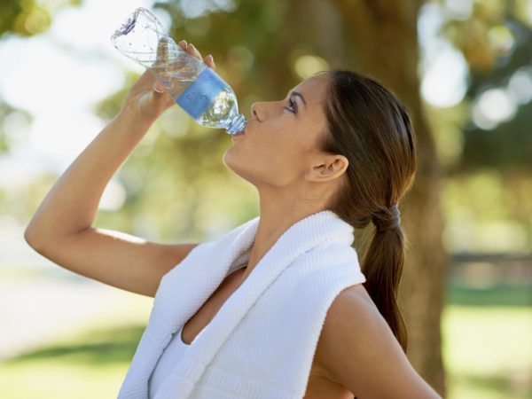 Cropped shot of a young woman drinking water after a workout