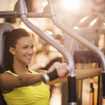 Happy woman working out on exercise machine in a gym.