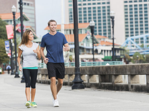 Mature couple jogging or power walking in the city, along a waterfront plaza.