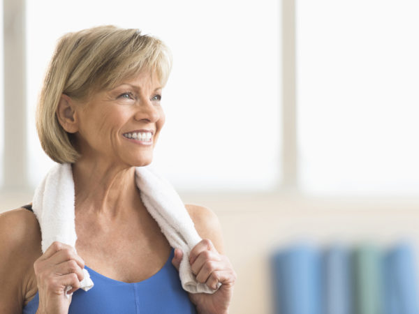 Happy mature woman with towel around neck looking away at home