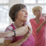 Group of seniors adults with Yoga Instructor. Instructor is helping senior woman with a yoga pose. Horizontal shot.