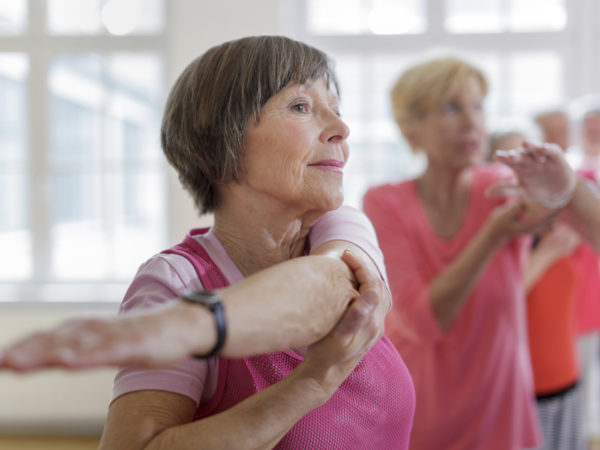 Group of seniors adults with Yoga Instructor. Instructor is helping senior woman with a yoga pose. Horizontal shot.