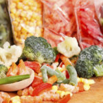 Mixed frozen vegetables on cutting board and plastic bags