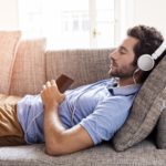 Young male couch listen headphones  mobile phone  at home