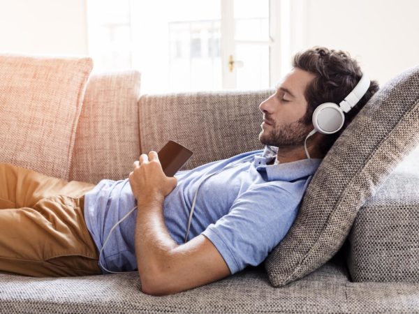 Young male couch listen headphones  mobile phone  at home