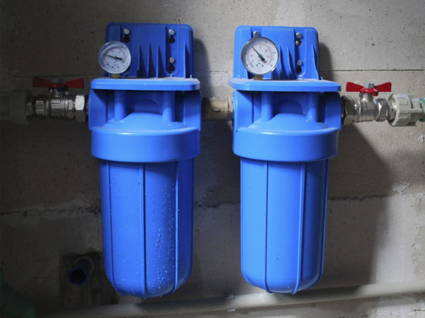 Two blue aqua filters with pressure meter. Set in a private home for purification of drinking water from wells.