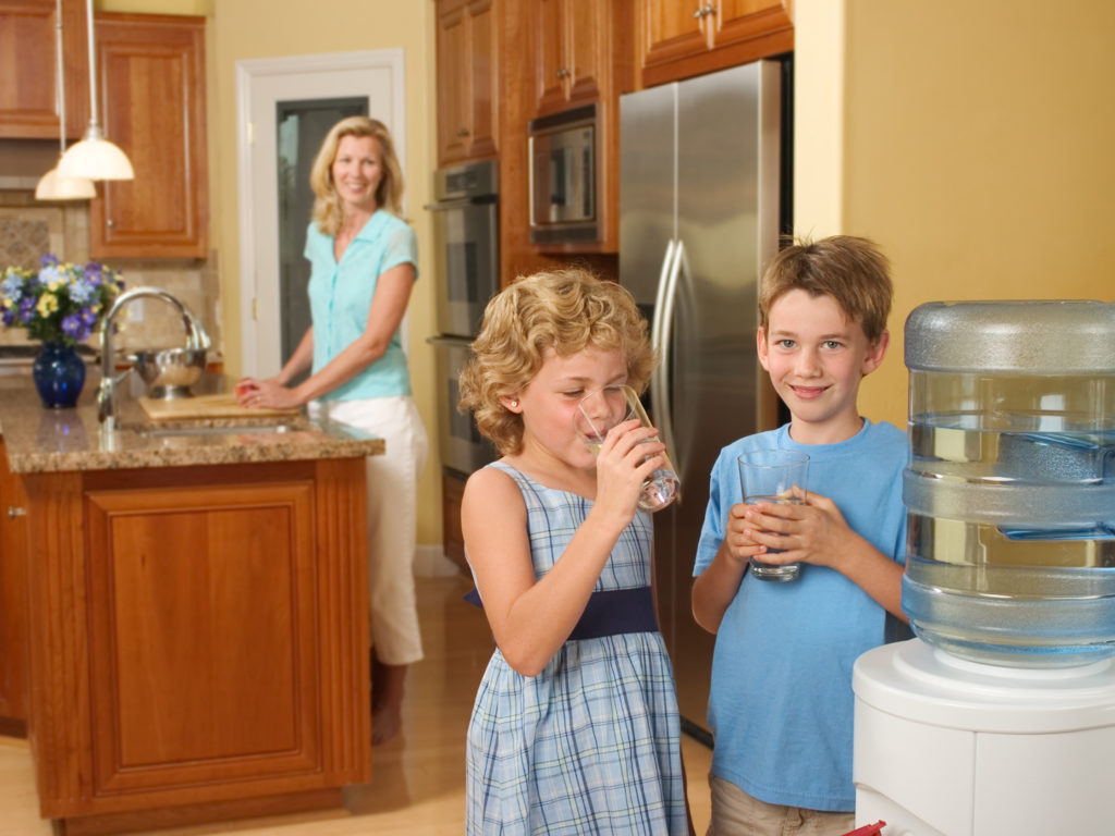 Children at home drinking purified water from a water cooler.