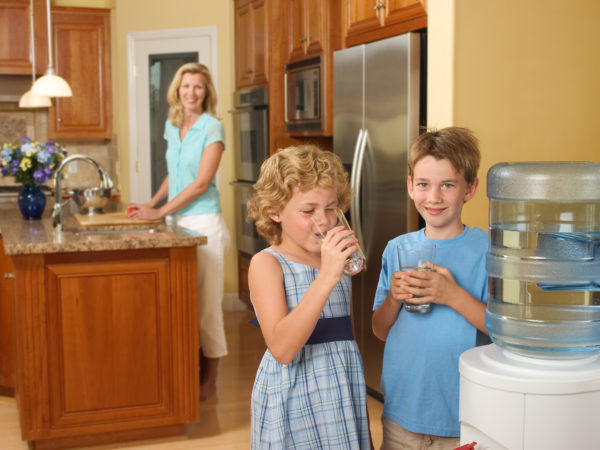 Children at home drinking purified water from a water cooler.