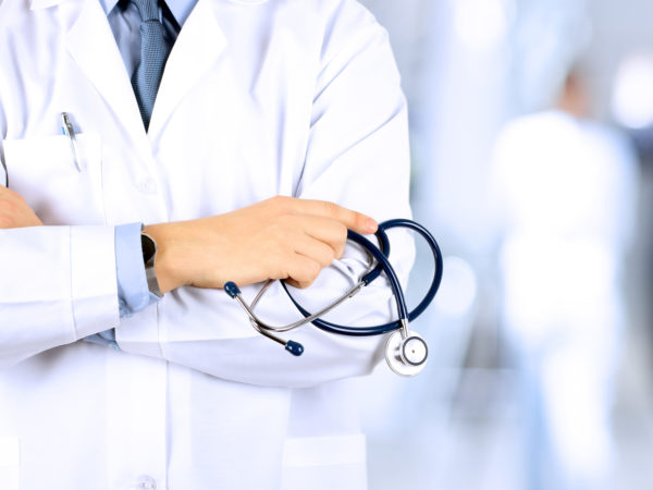 Portrait an unknown male doctor holding a stethoscope behind