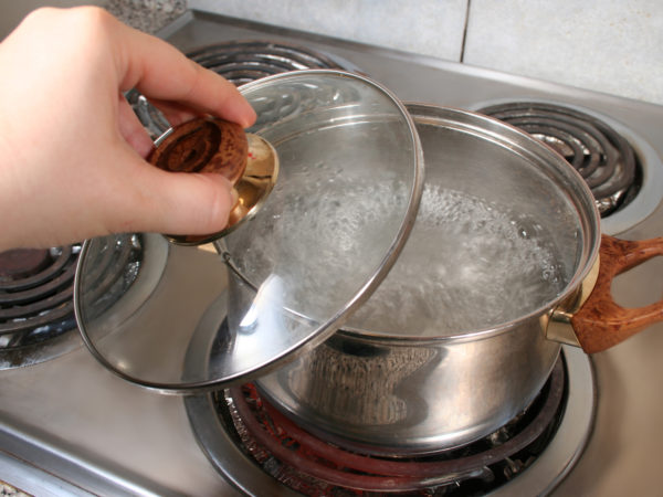 lifting lid of pot full of boiling water