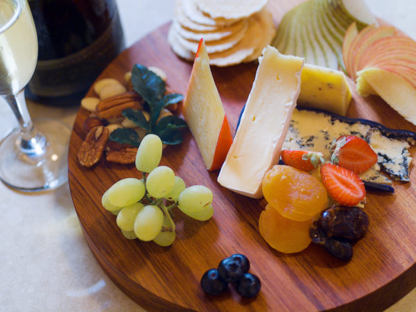 Overhead view of a cheese and fruit platter with sparkling wine