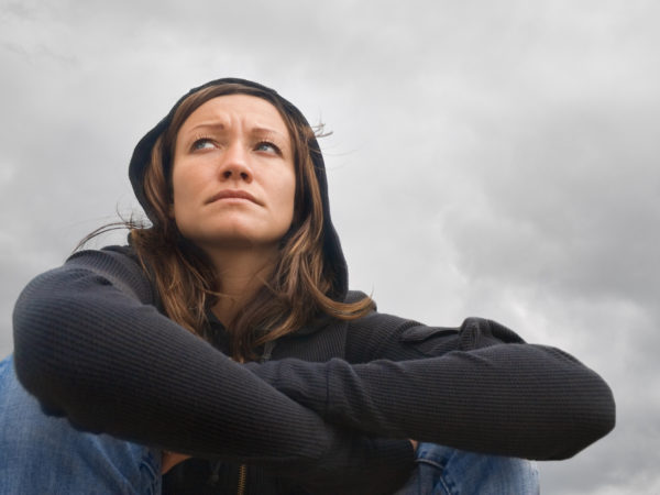 Girl sitting and contemplating on a background of a cloudy sky