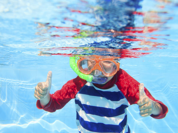 cute happy little boy swimming underwater with thumbs up