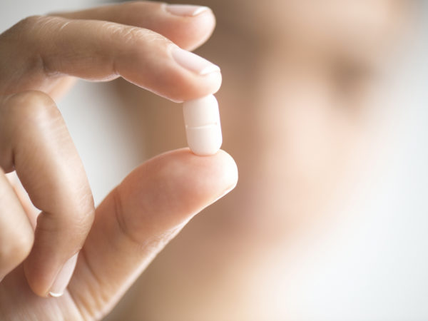 Woman holding medication capsule.