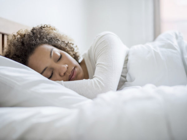 Tired black woman sleeping and looking very comfortable in her bed